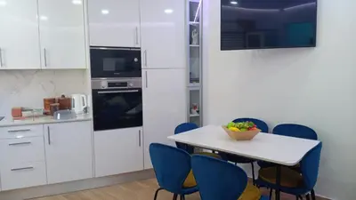 a kitchen with white cabinets and a table with blue chairs at Casa Tapada do Bento III- Albufeira in Albufeira