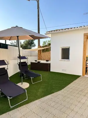 a patio with lawn chairs and an umbrella at Casa Rústica em Loulé - Karmea's Houses in Loulé