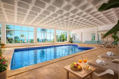 a pool in a living room with a table and chairs at Ocean Bliss II- Panoramic Sea View - 20m to Beach - 2 Swimming Pools - Private Parking in Albufeira