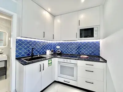 a kitchen with white cabinets and a blue tiled wall at Almancil Typical House by Homing in Almancil