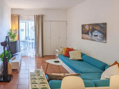 a living room with a blue couch and a tv at Sunset in Albufeira