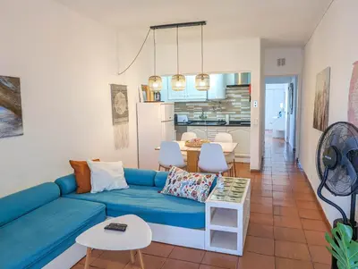 a living room with a blue couch and a kitchen at Sunset in Albufeira