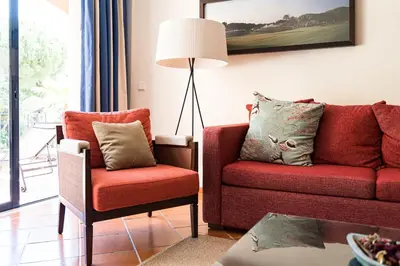 a living room with a red couch and a chair at Vila Sol F5 W Golf and Pool Apartment in Vilamoura