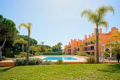 a villa with a swimming pool and palm trees at Vila Sol F5 W Golf and Pool Apartment in Vilamoura