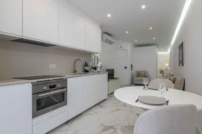 a kitchen with white cabinets and a white table and chairs at Baleeira Sea View Studio in Albufeira