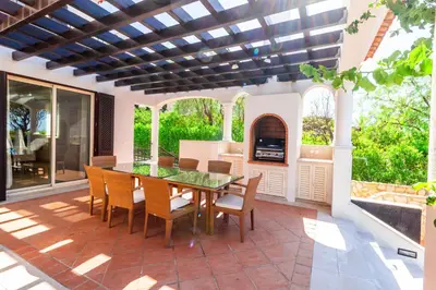 an outdoor patio with a table and chairs and a fireplace at Dunas Douradas Beach Club in Vale do Lobo