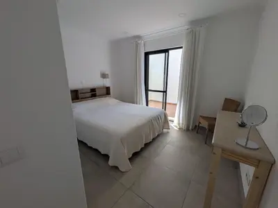 a bedroom with a bed and a desk and a window at Solar dos Pinheiros T3 in Vilamoura