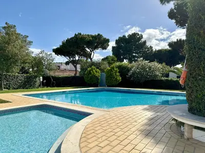 a swimming pool in a yard with a bench next to it at Solar dos Pinheiros T3 in Vilamoura