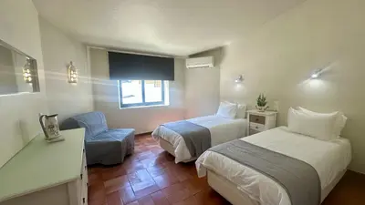 a hotel room with two beds and a chair at Tropicana by Check-in Portugal in Albufeira