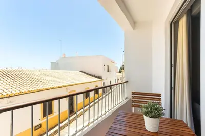 a balcony with a wooden table and a window at Gorgeous Flat 3min Walk to Beach in Albufeira