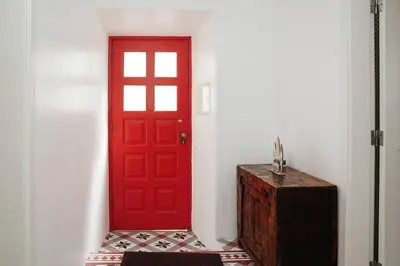 a red door in a white room with a wooden box at Breathtaking BeachFront House in Albufeira