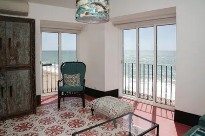 a living room with a chair and views of the ocean at Breathtaking BeachFront House in Albufeira