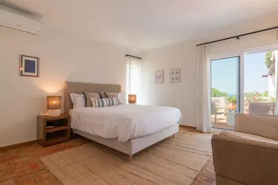 a white bedroom with a bed and a couch at Vila Antic in Almancil