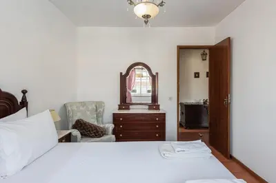 a bedroom with a bed and a chair and a mirror at Vila Coelho - City center with pool by HD in Vale de Pedras