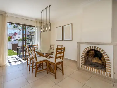 a dining room with a fireplace and a table and chairs at Duplex T2 com terraço e BBQ em Vilamoura in Quarteira