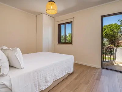 a bedroom with a white bed and a window at Duplex T2 com terraço e BBQ em Vilamoura in Quarteira