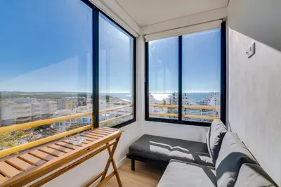 a room with large windows with a couch and a bench at Mar Azul 2 Bdr Apartment Quarteira in Quarteira