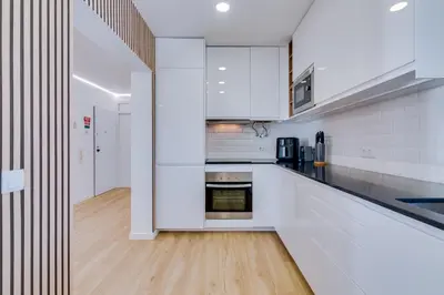 a kitchen with white cabinets and a wooden floor at Mar Azul 2 Bdr Apartment Quarteira in Quarteira