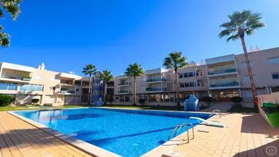 a swimming pool in front of a building with palm trees at Marina Sol - CD 308, Cleverdetails - great location in Vilamoura
