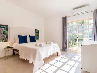 a white bedroom with a bed with blue pillows at Villa Paradis Paraiso com piscina privada em Albufeira in Albufeira