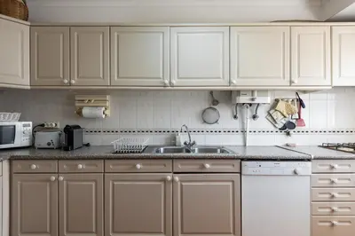 a kitchen with white cabinets and a sink at NEW! Vilamoura Garden View in Quarteira