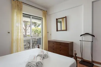a bedroom with a bed with white sheets and a window at NEW! Vilamoura Garden View in Quarteira