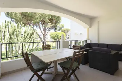 a dining room with a table and chairs and a balcony at NEW! Vilamoura Garden View in Quarteira