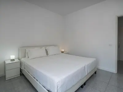 a white bedroom with a large white bed with two lamps at Algarsol 1bdr apartment near the beach in Quarteira
