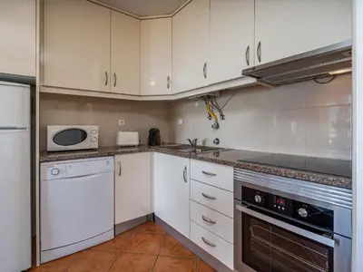 a kitchen with white cabinets and a stove top oven at T1 com Varanda e vista mar a 200m da Praia in Quarteira