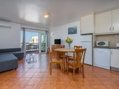 a kitchen and dining room with a table and chairs at T1 com Varanda e vista mar a 200m da Praia in Quarteira