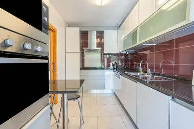 a kitchen with white cabinets and a black counter top at Vitismar GroundFloor Apartment with Direct Pool Access in Albufeira in Guia