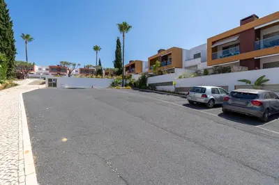 two cars parked in a parking lot next to a building at Vitismar GroundFloor Apartment with Direct Pool Access in Albufeira in Guia