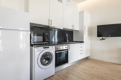 a kitchen with a washing machine and a tv at Downtown Studio Apartment F - 150m from the Beach in Albufeira