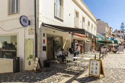 a group of people sitting at tables outside a building at Downtown Studio Apartment G - 150m from the Beach in Albufeira