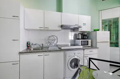 a kitchen with white cabinets and a washing machine at Faro Downtown Suites - Vila Adentro in Faro