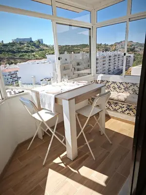 a white table and chairs in a room with windows at Charmoso T1 Varandas de Malpique in Albufeira