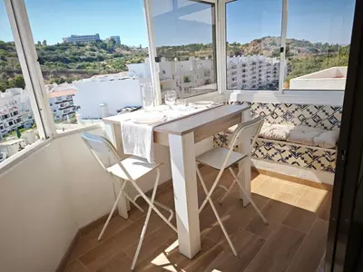 a white table and chairs in a room with windows at Charmoso T1 Varandas de Malpique in Albufeira