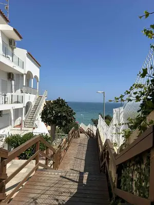 a wooden boardwalk leading to the beach with a building at Casa da Praia em Olhos de Água a 50 metros da Praia in Olhos de Água
