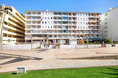 a large white apartment building next to a park at Paraná in Quarteira