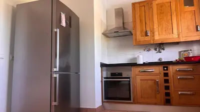 a kitchen with a stainless steel refrigerator and wooden cabinets at NEW! Casa do Praia Almancil in Almancil
