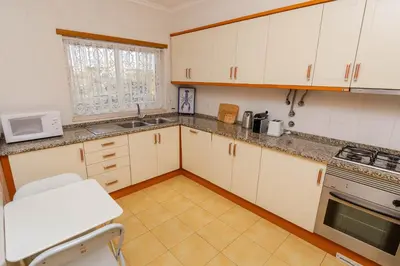 a kitchen with white cabinets and a sink and a microwave at Ver o Mar in Albufeira