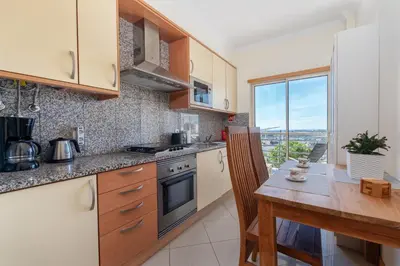 a kitchen with a wooden table and a counter top at BnB Homes Eco Apartment with Terrace, 2 Swimming pools & Tennis court in Albufeira