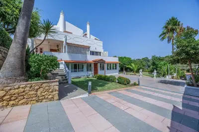 a large white building with a palm tree in front of it at Villa Saromani in Branqueira
