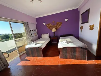 a room with two beds and a purple wall at Villa Saromani in Branqueira