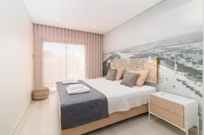 a bedroom with a large bed and a large window at São Luís Faro Apartment - Algarve in Faro