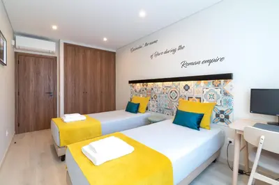 two beds in a room with a desk and a tv at São Luís Faro Apartment - Algarve in Faro