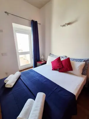 a bedroom with a large bed with blue and red pillows at Casa do Pino in Faro