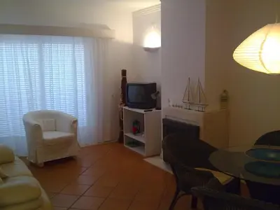 a living room with a couch and a tv and a table at Akisol Vilamoura Rise in Quarteira