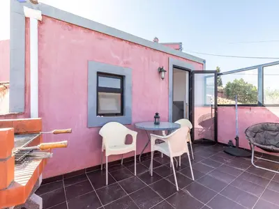 a patio with a table and chairs on a pink wall at Akivillas Loulé Holiday in Espargal