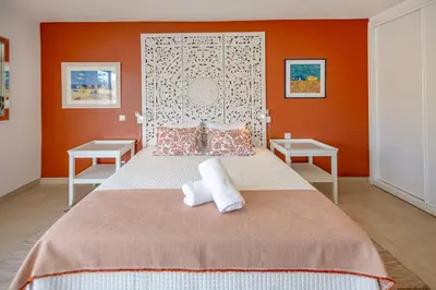 a bedroom with orange walls and a bed with two tables at Angela's in Albufeira